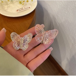 Detailed close-up of transparent and pink resin butterfly hair clips with textured wings