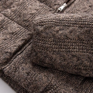 Detailed macro view of heavy brown cable knit texture and premium metal zipper closure
