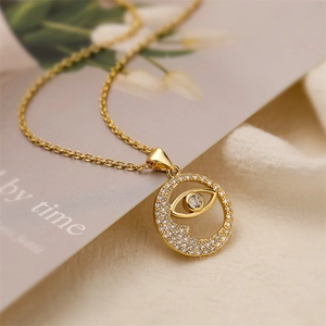 Detail of gold evil eye pendant with sparkling zircons on elegant cable chain