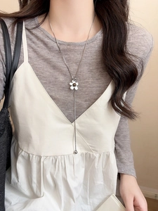 Detail of silver five-petal flower necklace featuring a zircon pendant with long tassel chain