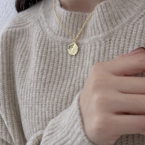 Detail of 925 sterling silver irregular wave pendant necklace on beige sweater