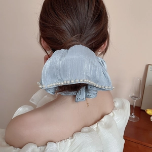 Close-up of light blue fabric hair scrunchie with elegant faux pearl trim and bow detail