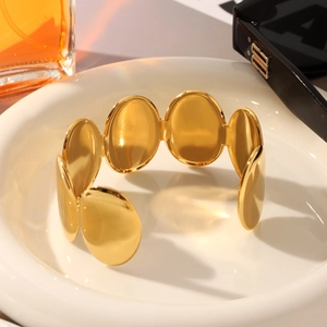 Macro detail of 18K gold plated stainless steel oval link bangle in a ceramic dish