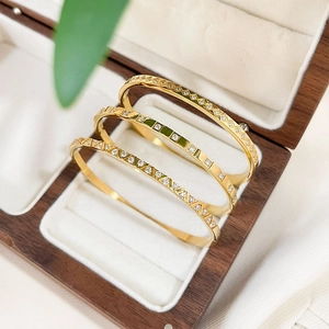 Three-piece geometric 18K gold plated bangle set with zircon accents on white velvet