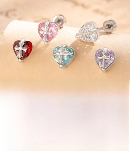 Macro shot of titanium steel heart studs with colorful zircons and cross details