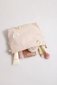 Dettaglio della borsa trucco beige a righe rosse con fiori 3D e etichetta del marchio