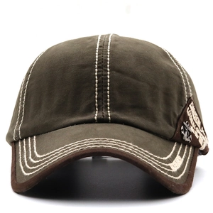 Detail of olive green canvas baseball cap with white contrast stitching and anchor patch