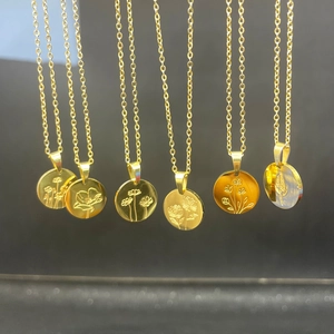 Macro shot of multiple gold stainless steel necklaces with various engraved floral pendants