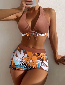 Detail of high-waist floral bikini bottoms and halter top with orange and blue botanical print