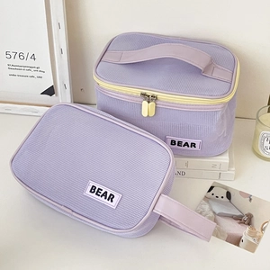 Detail of purple mesh toiletry bags with yellow zippers and white BEAR logo