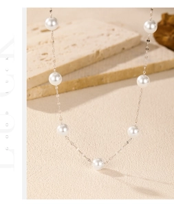 Detailed view of silver necklace with multiple white pearls spaced on a delicate chain