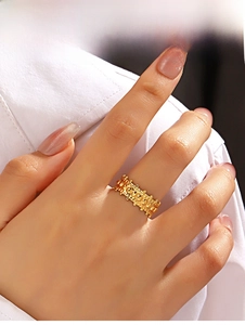Macro detail of gold irregular textured ring with embossed gear patterns on finger
