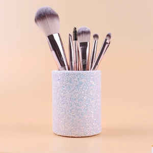 Close-up of makeup brushes with rose gold handles in a white iridescent sequin brush holder