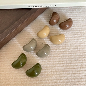 Set of four resin C-shaped bean earrings in earth tones on vintage wooden tray
