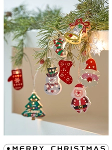 Close-up of wooden LED Christmas charms with warm glow nestled in festive pine branches