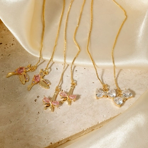 Elegant gold drop earrings with bird, tower, and bow pendants on beige stone and satin