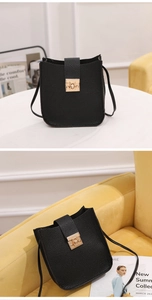 Gros plan sur un sac bandoulière en cuir grainé noir avec un fermoir doré carré rotatif
