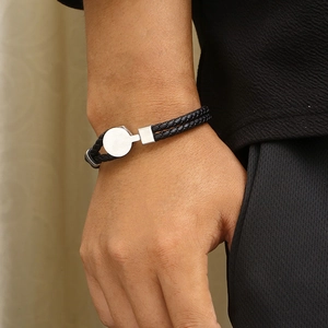 Double-layered braided leather bracelet with silver studs on male wrist in close-up shot