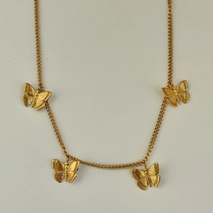 Detailed view of the gold butterfly necklace with intricate engraved texture on pendants