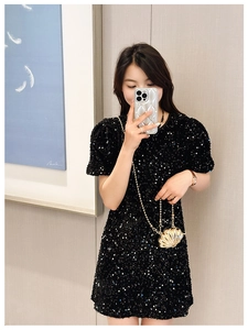 Chic golden shell-shaped mini bag worn crossbody with a black sequin dress in mirror selfie