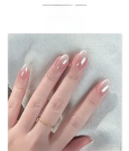 Detail of French white gradient press-on nails with glossy finish on a grey textured base