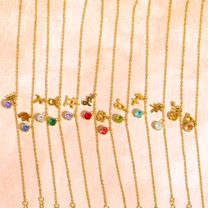 Detailed row of golden zodiac necklaces with colorful birthstones and engraved symbols
