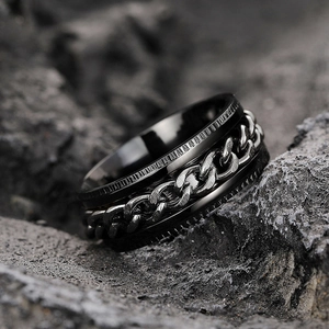 Men's industrial black stainless steel chain spinning ring on a dark rock background