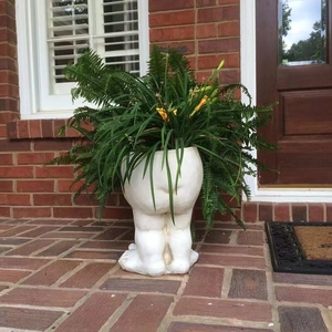 Funny white face statue planter featuring creative butt and feet design on stone floor