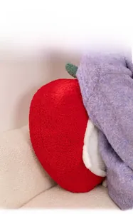 Detail of red apple plush pillow with green leaf made of soft granular fleece fabric