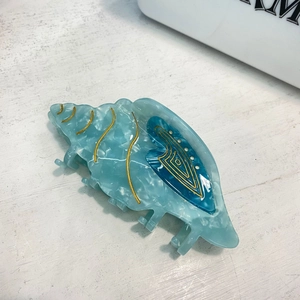 Blue seashell acetate hair claw clip with golden patterns on a clean white backdrop