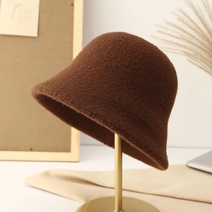 Detailed texture of dark brown plush wool bucket hat on a gold display stand
