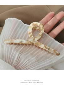 Large acetate hair claw clip with cream marble texture held against chiffon fabric