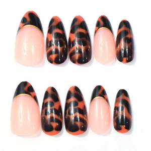 Detail of short almond press-on nails featuring leopard print and gold-lined French tips