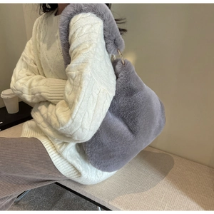 Gros plan d'un sac cabas en peluche grise porté par un mannequin en intérieur épuré