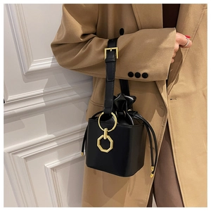 Detail of a black leather bucket bag featuring a unique gold octagonal metal ring accent
