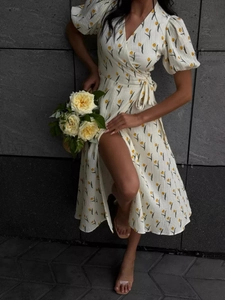 Detail of floral wrap dress with puff sleeves and yellow tulip print on off-white cotton