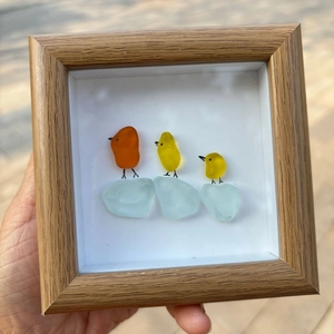 Détail de l'art en verre de mer avec oiseaux colorés et cadre en bois naturel