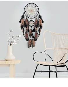 Bohemian dream catcher with brown feathers hanging on a gray wall in a minimalist room