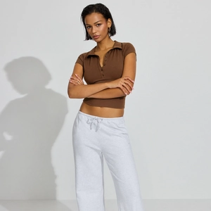 Detailed view of women's brown slim fit polo shirt paired with grey drawstring joggers