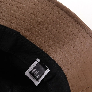 Macro detail of brown litchi leather sun hat showing fine stitching and inner fabric lining