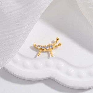 Vue macro d'un pendentif insecte doré orné de strass brillants sur tissu blanc