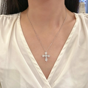 Close-up of a silver cross pendant necklace with zircon stones worn by a model