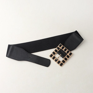 Detail of a 6cm wide black elastic belt with a large gold square buckle and acrylic inlay