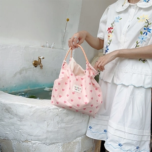 Detail of pink heart tote bag with woven handles and signature woven label brand tag