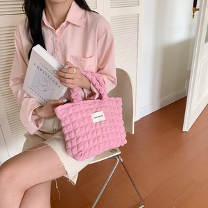Detail of pink bubble textured fabric handbag shown in a lifestyle indoor fashion setting