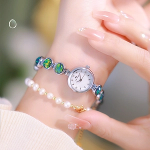 Detail of vintage luxury quartz watch with green opal style strap and pearl bracelet