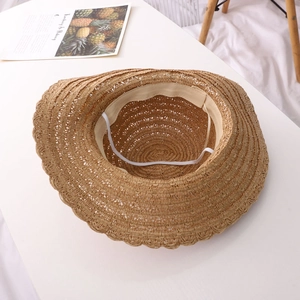 Detailed view of handmade woven straw hat featuring wave brim and elastic chin strap