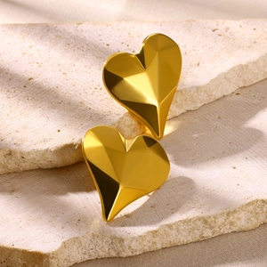 Macro shot of gold-plated 3D heart stud earrings featuring faceted geometric textures