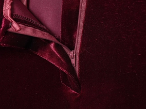 Detailed macro view of the zipper on wine red velvet fabric showing high-end texture