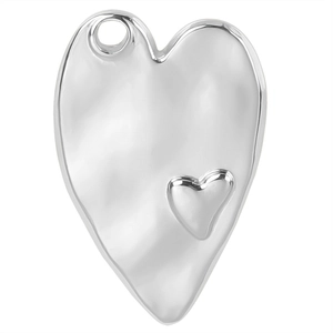 Detailed view of a silver heart pendant made of polished stainless steel with a small embossed heart